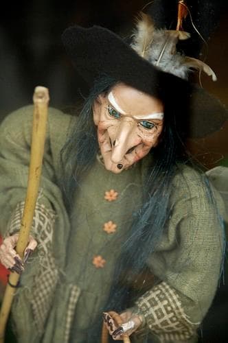 Puppet witch in a green dress holding a broomstick